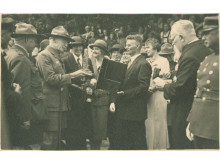 Robertas Baden-Powellis apžiūri įteiktą dovaną – gintarinį suvenyrą. 1933 m. rugpjūčio 17 d. Fotografas nežinomas. Iš Nacionalinio M. K. Čiurlionio dailės muziejaus rinkinių.