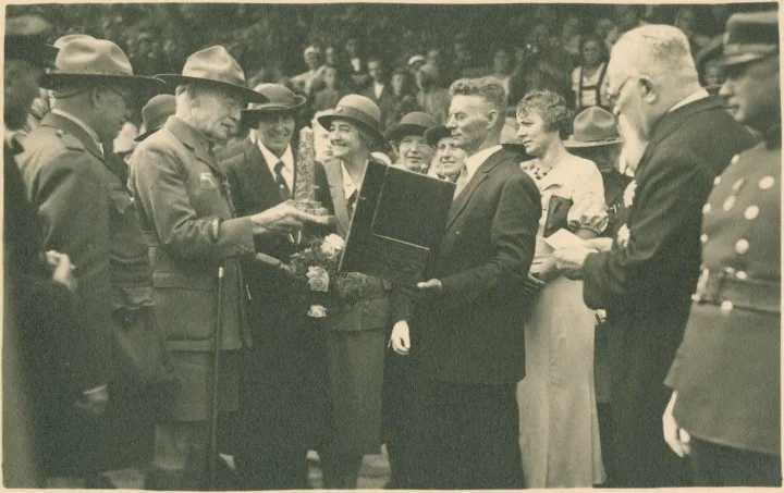 Robertas Baden-Powellis apžiūri įteiktą dovaną – gintarinį suvenyrą. 1933 m. rugpjūčio 17 d. Fotografas nežinomas. Iš Nacionalinio M. K. Čiurlionio dailės muziejaus rinkinių.